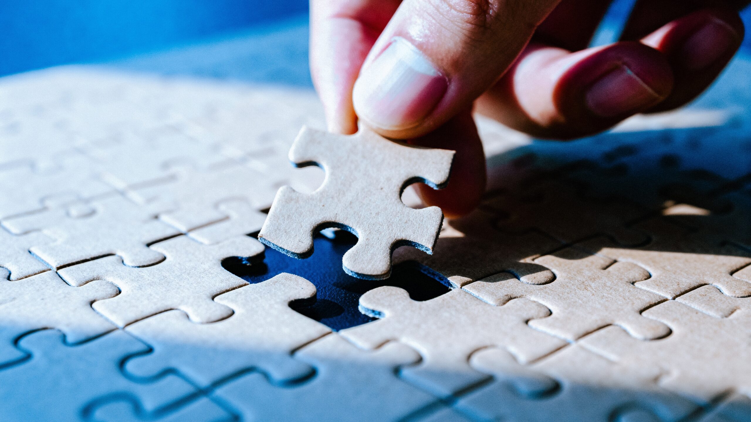 hand placing puzzle piece in empty space of puzzle