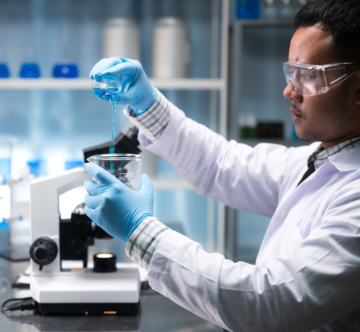 man in labcoat working using microscope