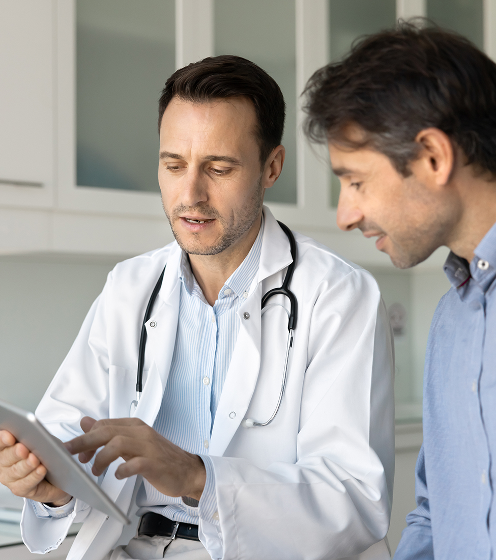 doctor in white coat, with stethoscope around his neck speaking to patient